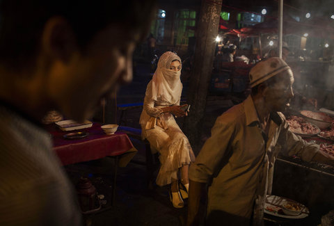 A veiled Uyghur woman sitting at a food stall in Kashgar.